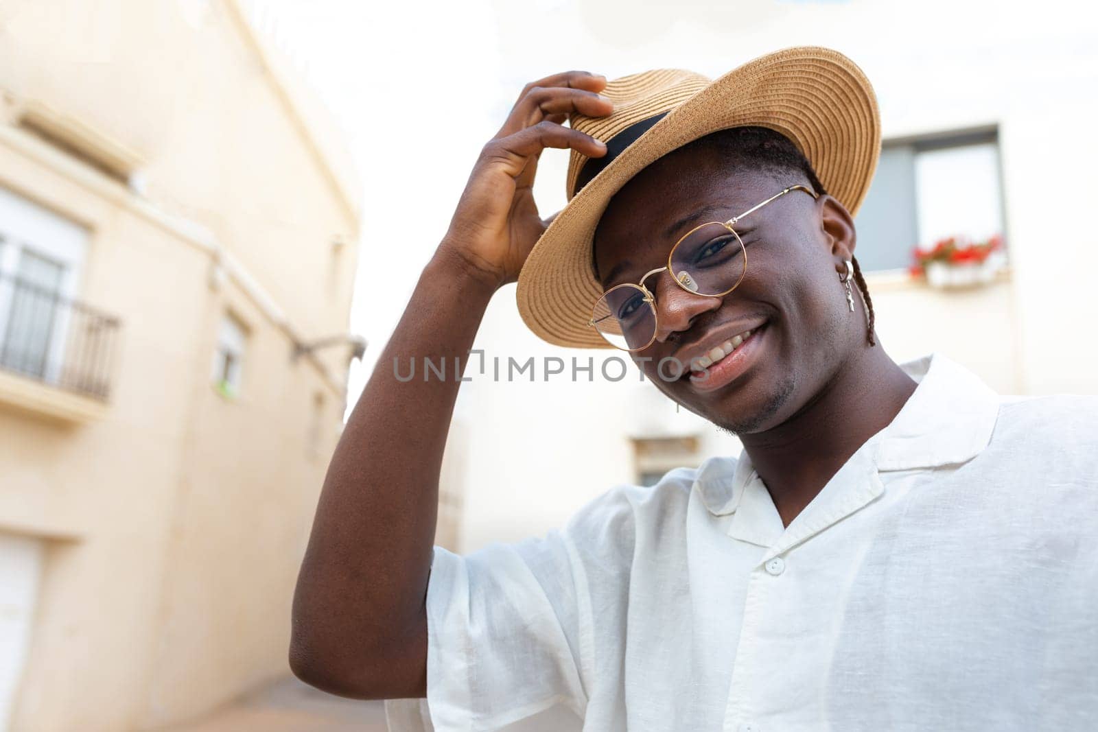 Young African American man wearing a hat on vacations looking at camera. by Hoverstock