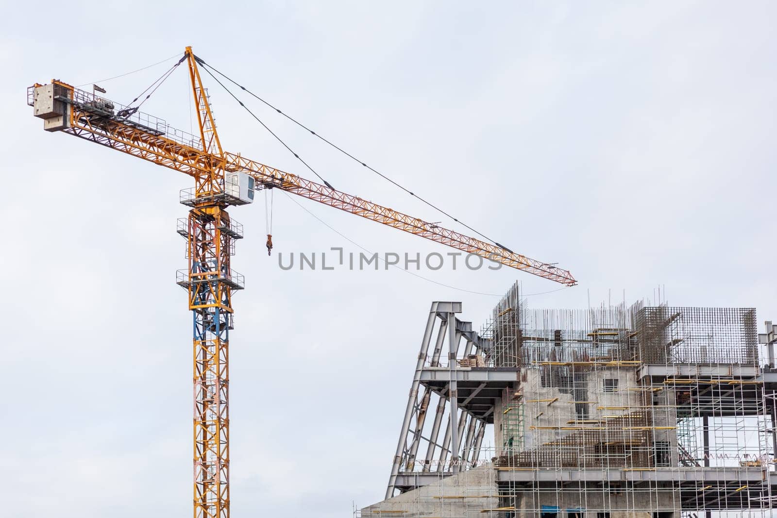 Construction of a large concrete building. Construction crane on the background of the sky. Construction site.