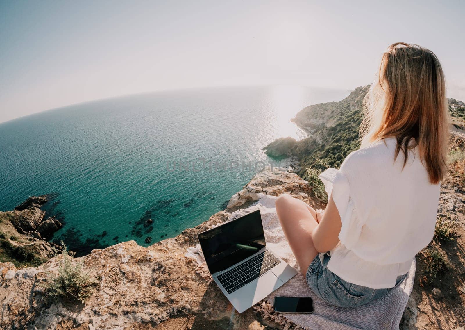 Woman sea laptop. Business woman in yellow hat working on laptop by sea. Close up on hands of pretty lady typing on computer outdoors summer day. Freelance, digital nomad, travel and holidays concept.