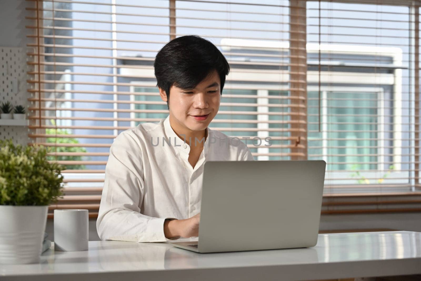 Handsome male marketing business manager sitting in modern office and using laptop computer. Business technologies concept by prathanchorruangsak