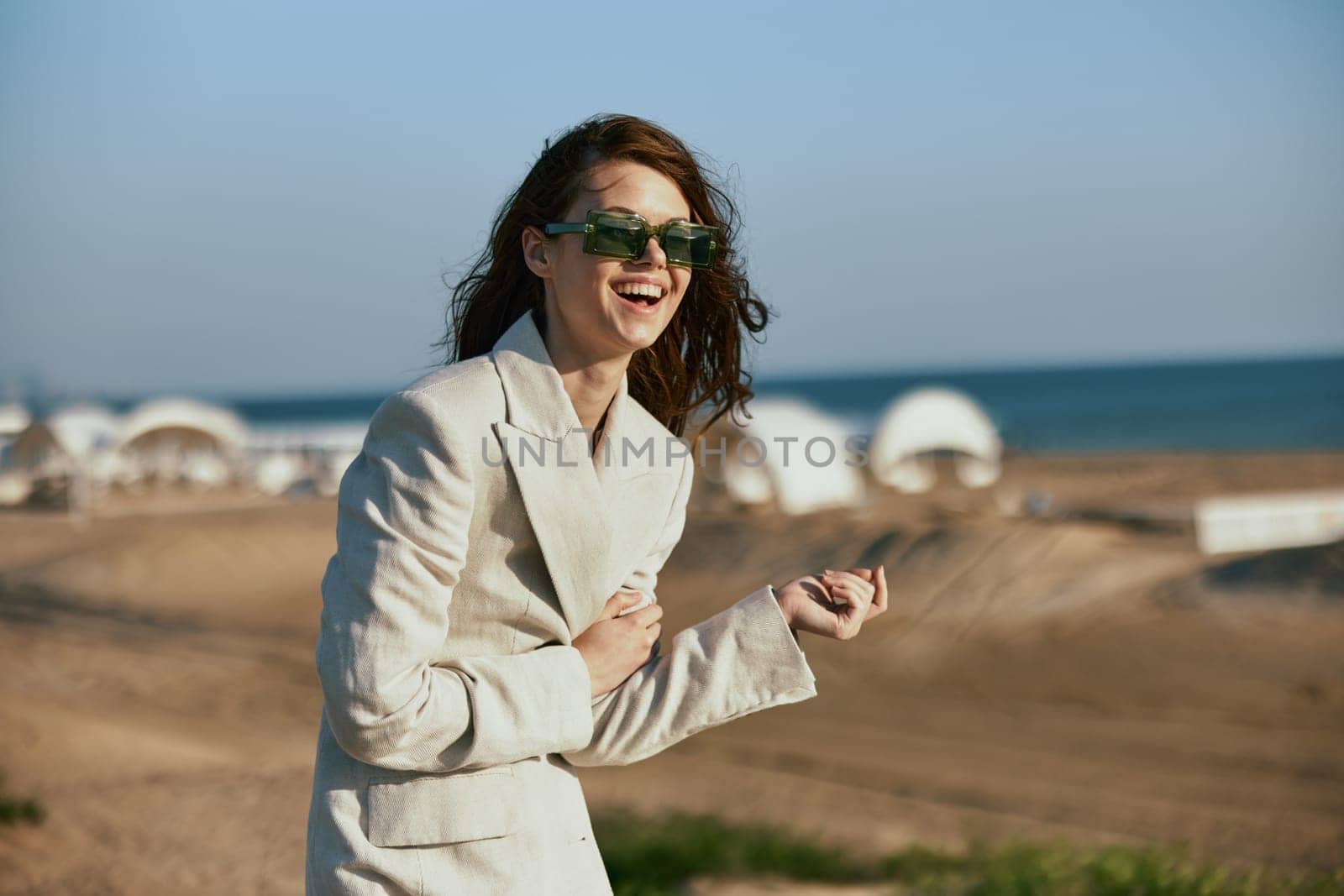 stylish woman with red hair standing on the coast in sunglasses laughing. High quality photo