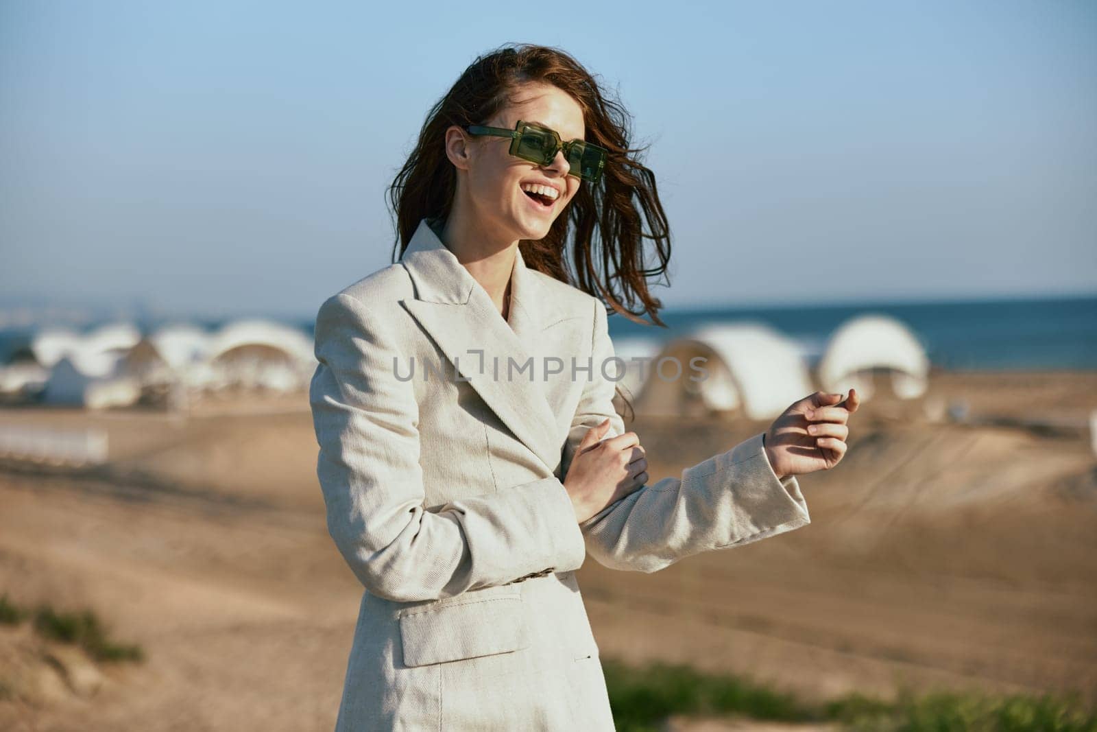 stylish woman with red hair standing on the coast in sunglasses laughing by Vichizh