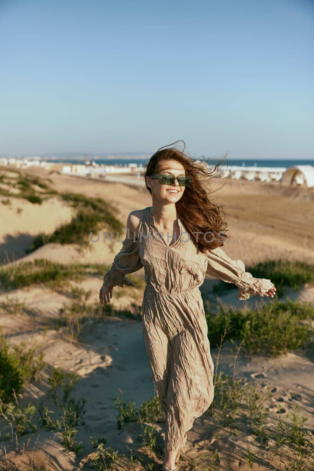 stylish woman, in summer, walks on the coast in windy weather enjoying vacation by Vichizh