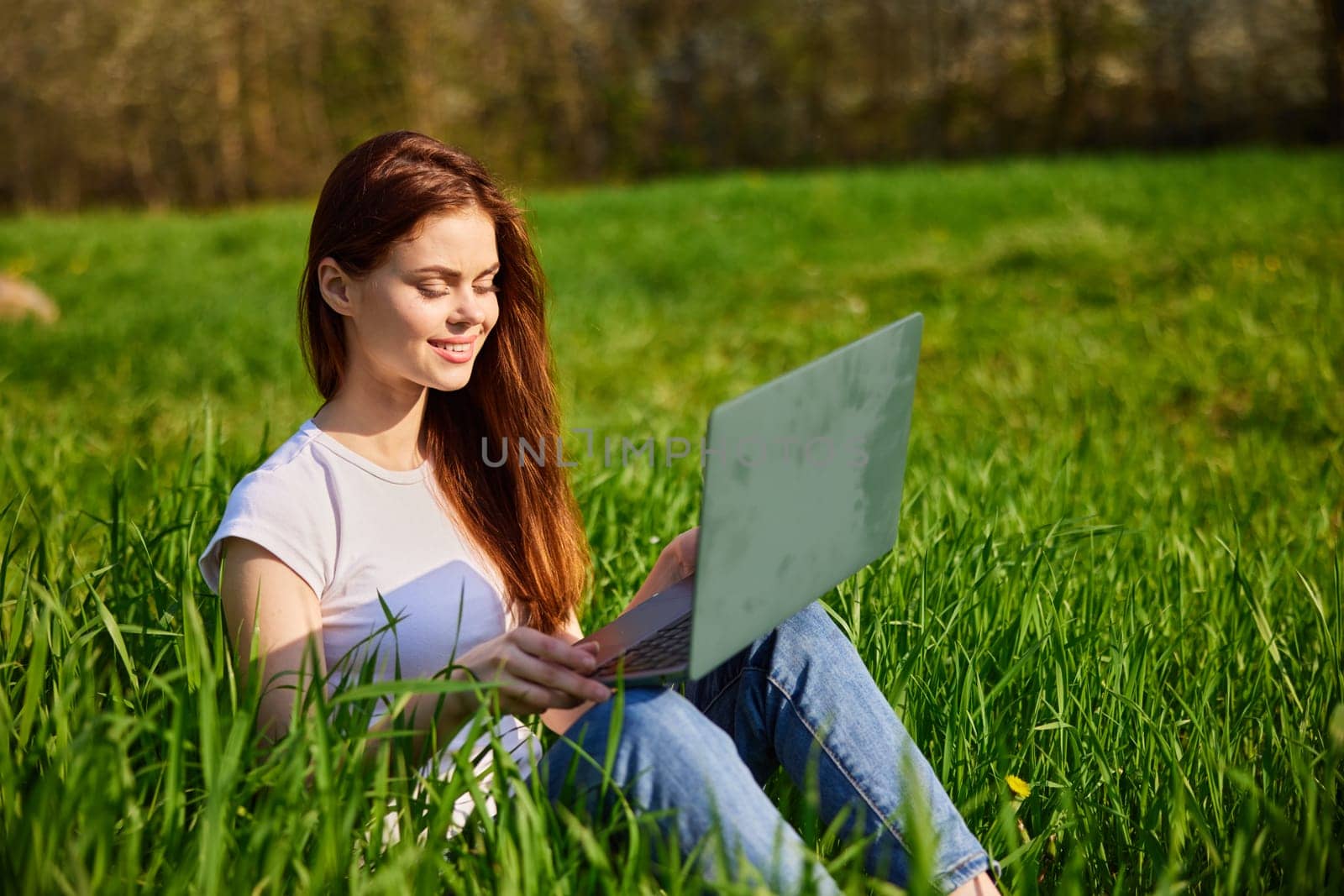 woman in nature working on a laptop on a sunny day. High quality photo