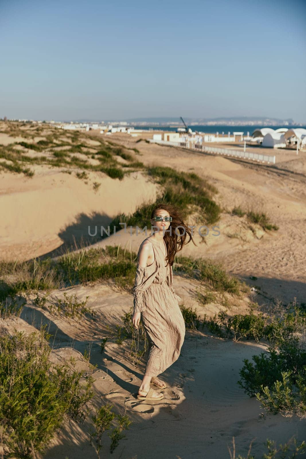 a woman on vacation walks along the promenade in a long dress and sunglasses. High quality photo