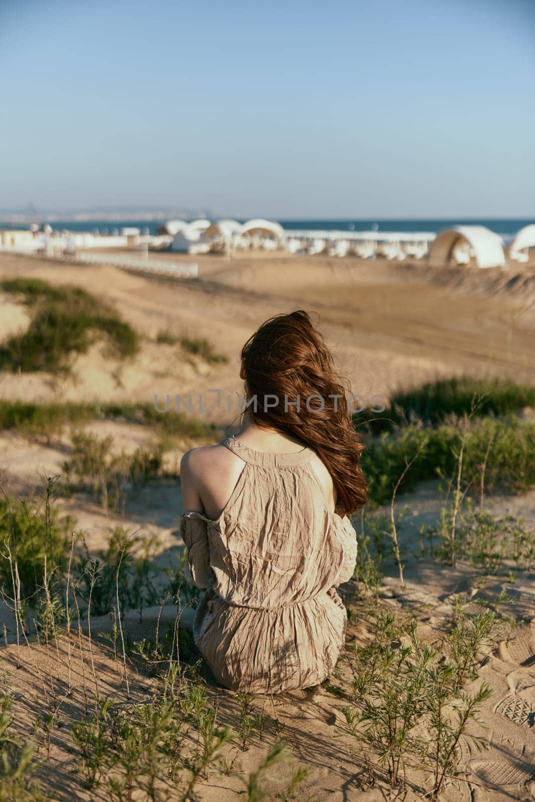 a woman sits with her back to the camera on the sea coast enjoying the sea view by Vichizh