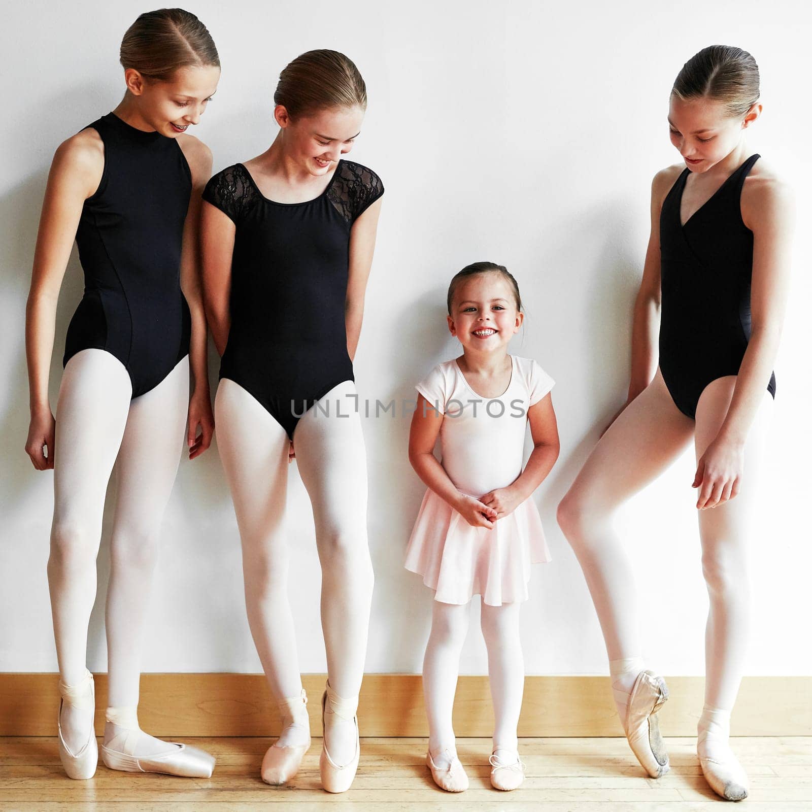 Little girl, big ballerina dreams. a group of young ballerinas teaching a little girl ballet in a dance studio