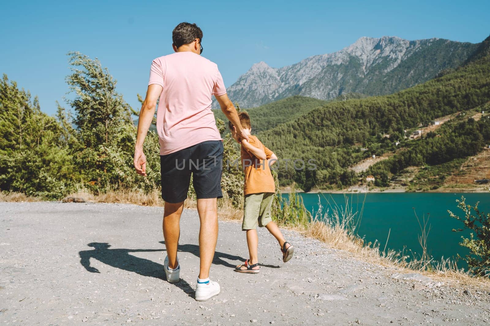 Young dad and his son standing on Mountain View. Child kid boy having fun with father and hiking hiking near mountains lake on background.
