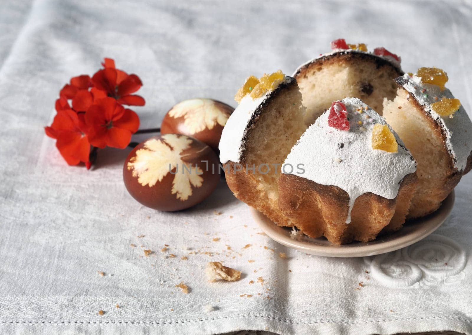 The concept of delicious Easter food, close-up.Easter homemade pastries displayed with eggs and a flower on a white natural tablecloth