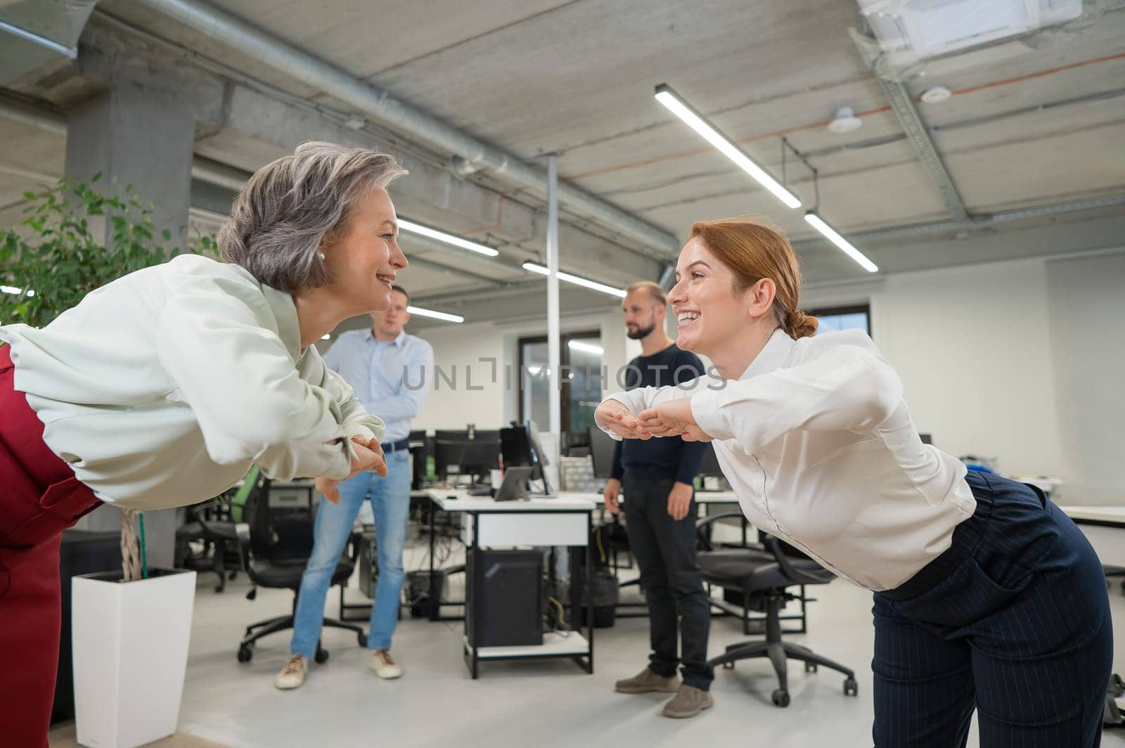 Four office workers warm up during a break. Employees do fitness exercises at the workplace. by mrwed54