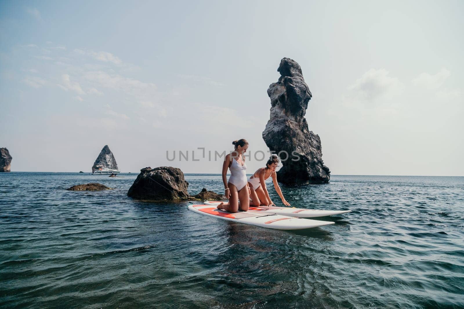 Woman sup yoga. Middle age sporty woman practising yoga pilates on paddle sup surfboard. Female stretching doing workout on sea water. Modern individual hipster outdoor summer sport activity