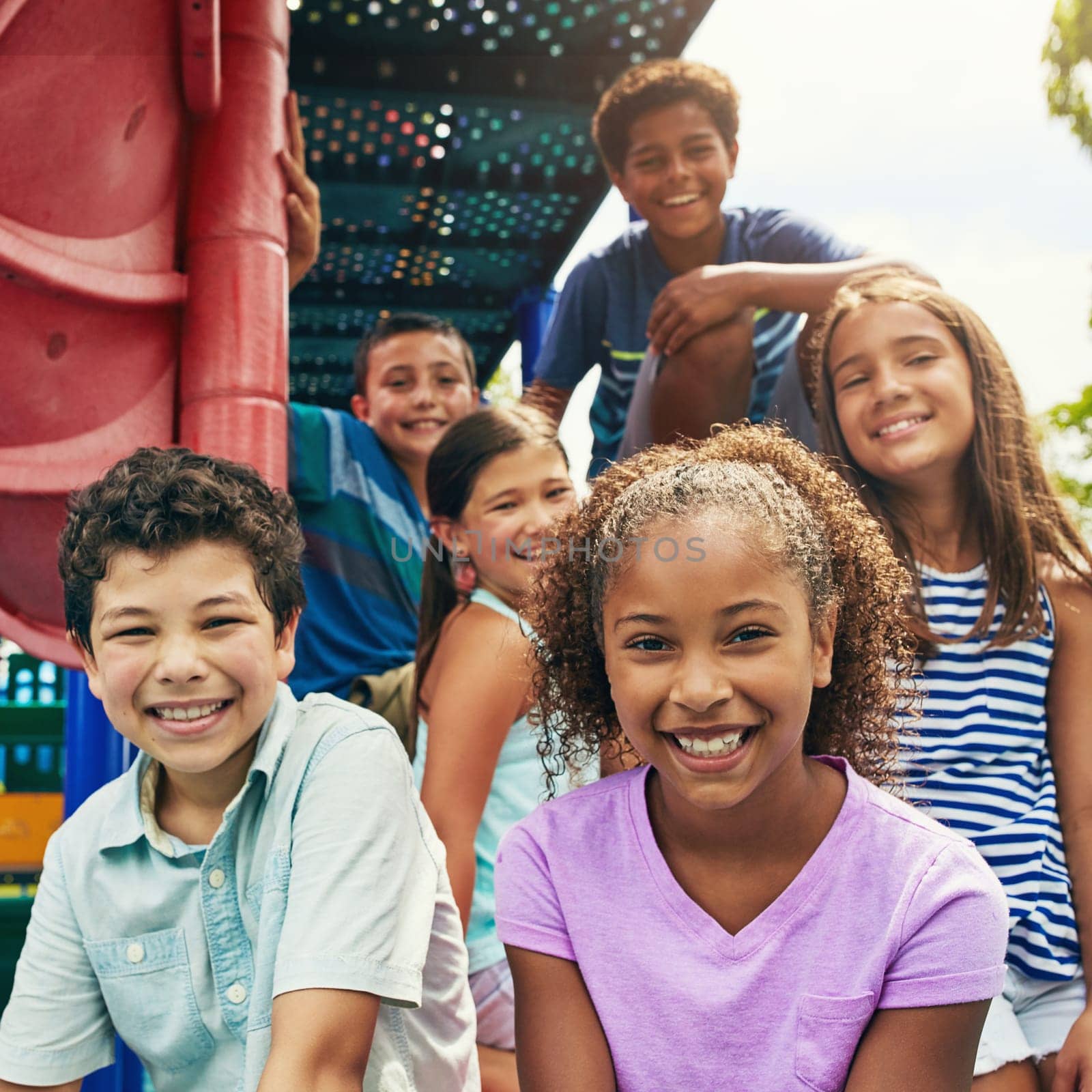 Childhood is all about having fun. a group of young friends hanging out together at a playground. by YuriArcurs