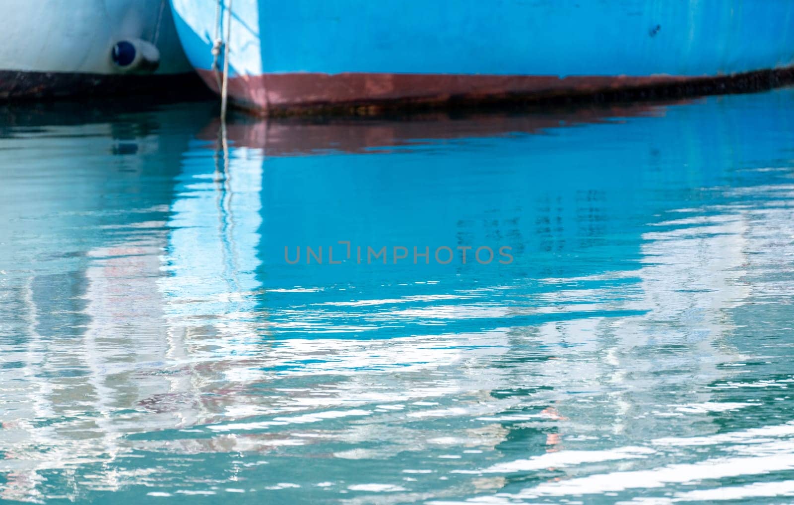 Reflection in the sea surface of white yachts parked in the port on the shore. Fragment of a ship on the water and the reflection of ships in the sea. motionless mirrored water of the sea.