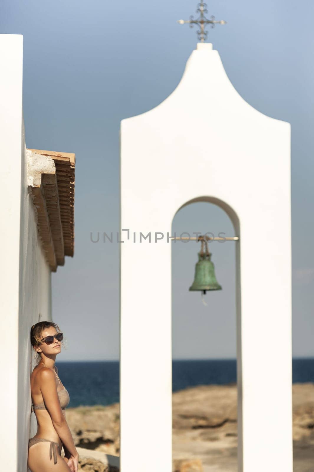 Young woman in a swimsuit on the background of Greek architecture and the sea. Woman in sexy bikini and santoini landscape.