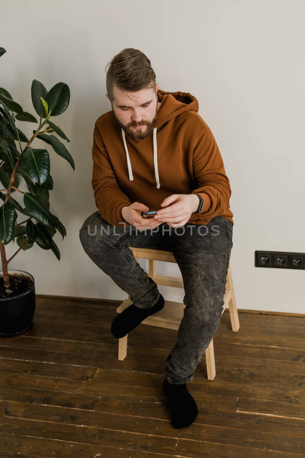 Freelance man using mobile phone checking social media network feed or message chat sitting on bed at home. Online digital communication rest after hard work day