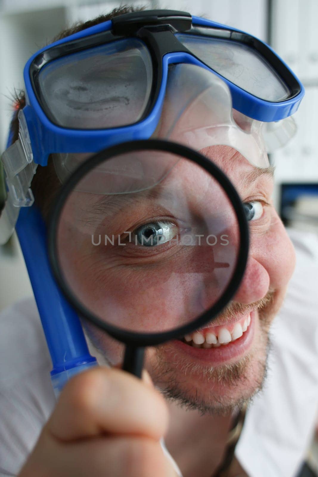 Portrait of a happy smiling manager in swimming goggles looks through magnifying glass. Search and booking tourist travel for tourists