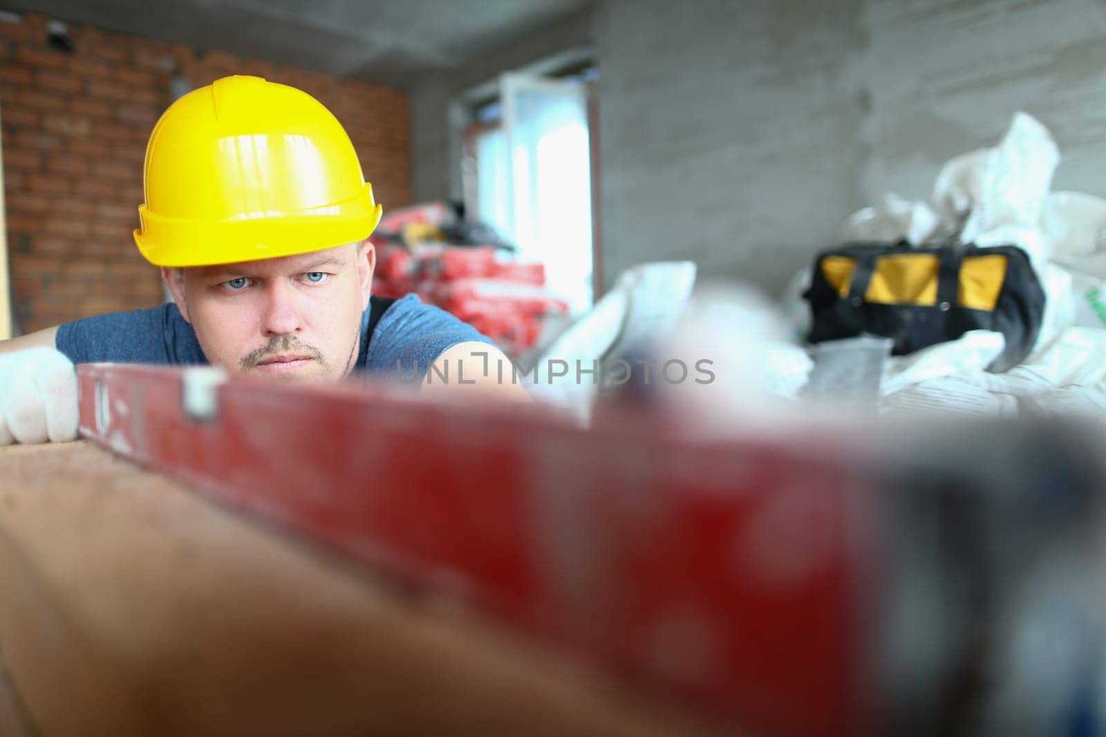 Bricklayer checks evenness of brick wall, brick foundation using spirit level. Brickwork walls and mason services