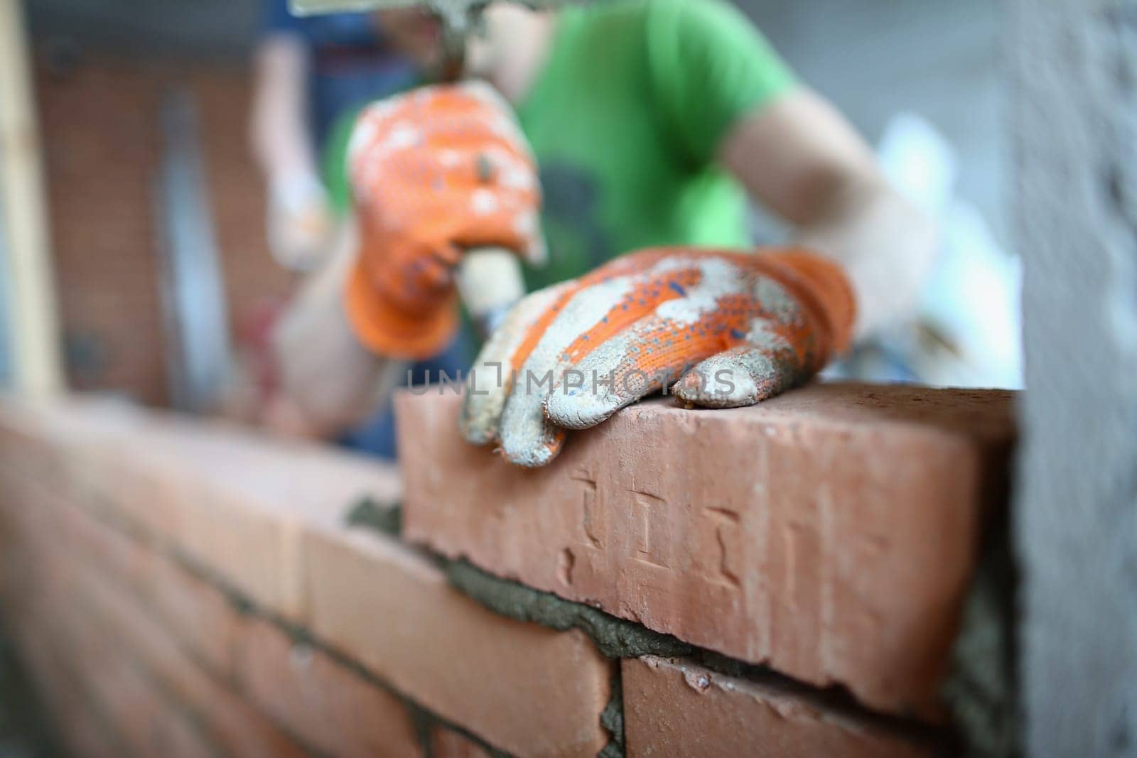 Bricklayer lays bricks on cement building exterior or interior walls. Brickwork of walls in private houses and apartments