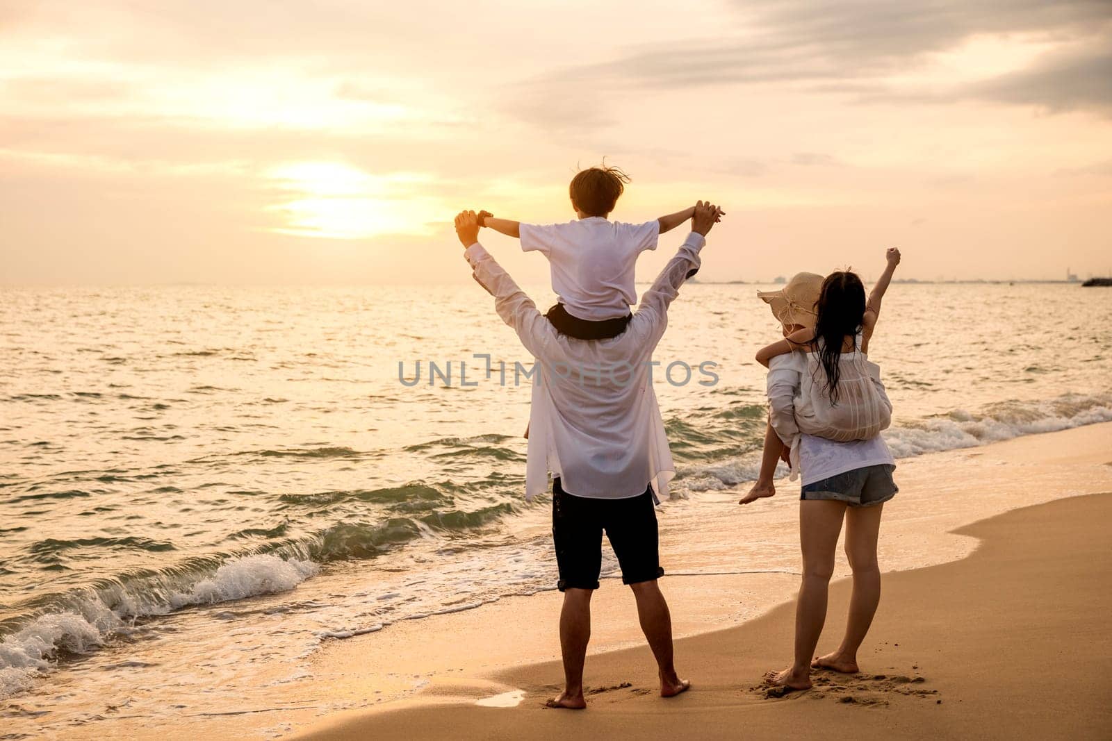 Father carrying son and Mother carrying daughter on shoulder walking summer beach by Sorapop
