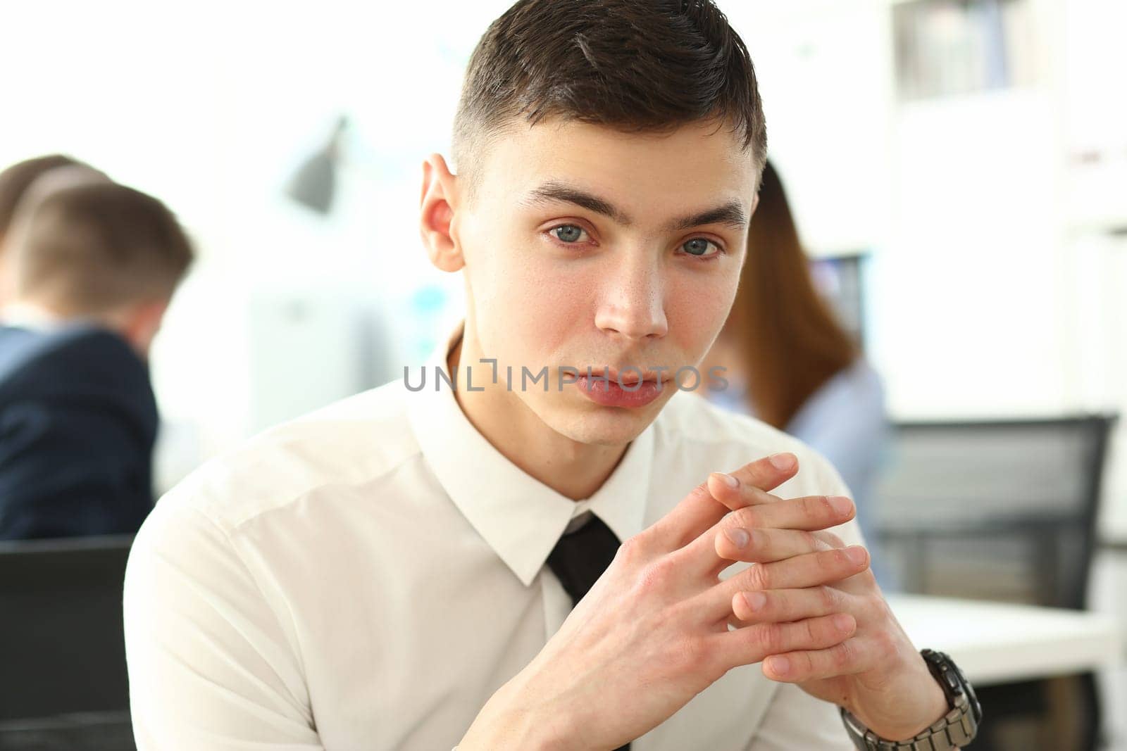 Portrait of young man at desk in office. Smart successful trainee in business company