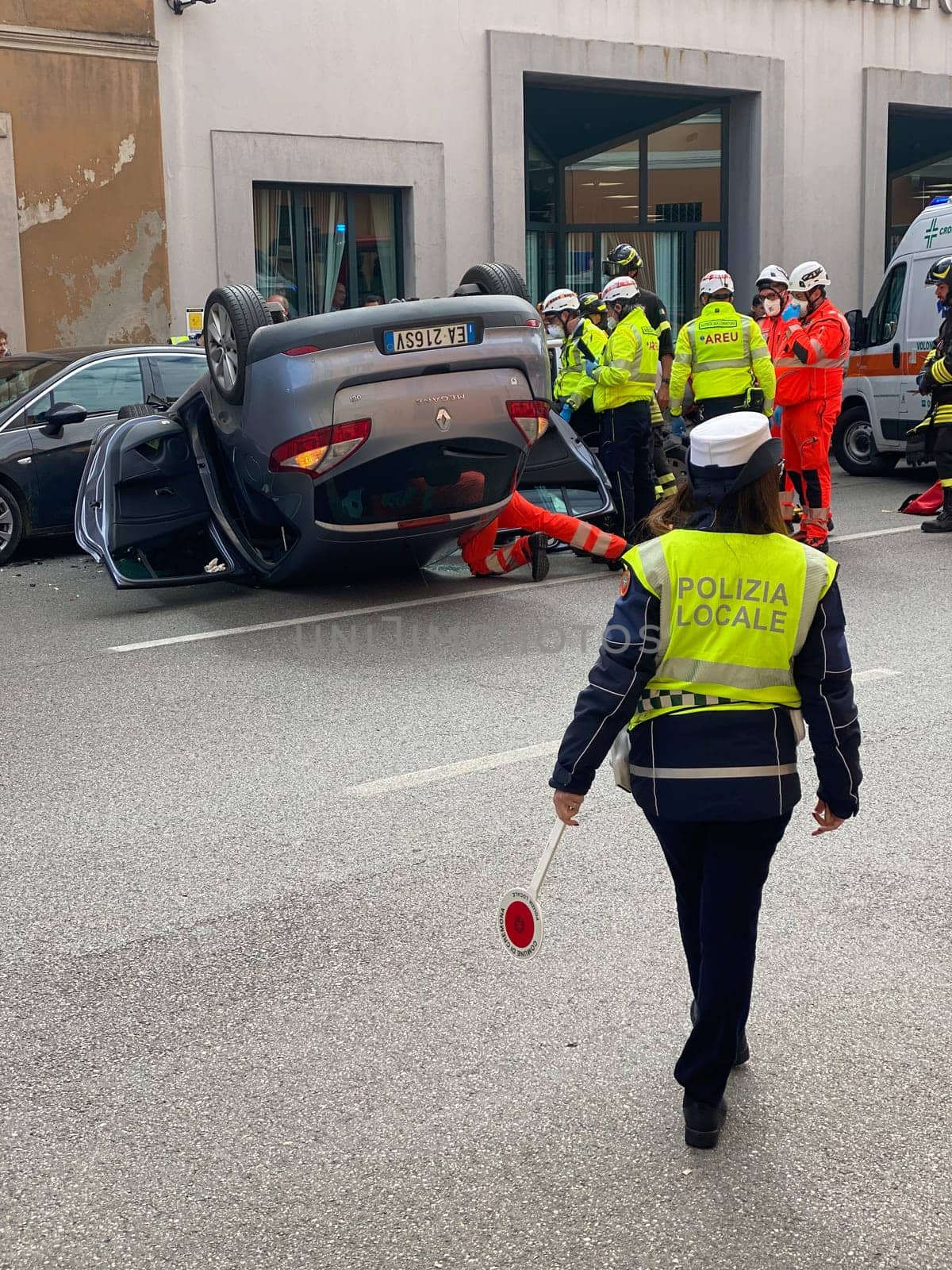 Cremona, Italy - 18th April 2023 just rolled over crashed car after an accident, police officer helping with traffic