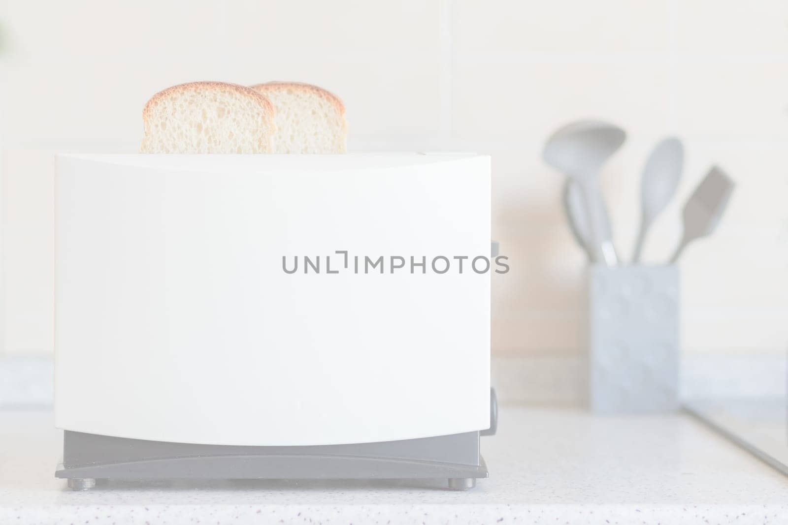 Light overexposed kitchen background with toaster and kitchen utensils on the table.