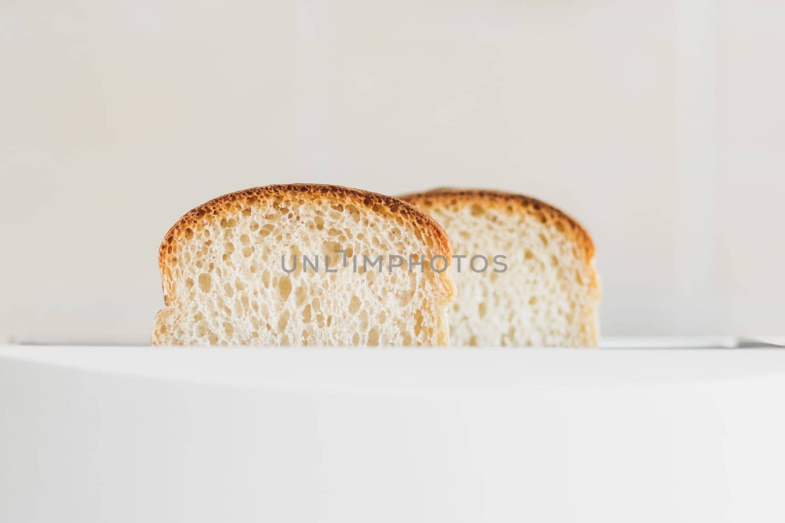 Front view on sliced fresh bread inserted into a white toaster, selective soft focus, copy spce.