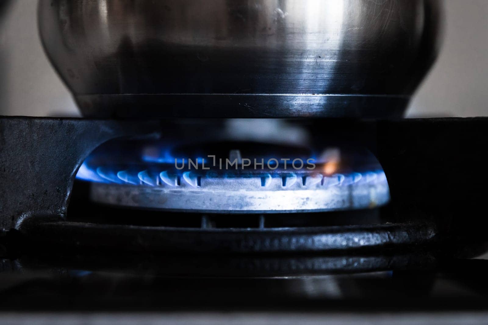 Flame from natural gas on a stove burner with a cooking pot.