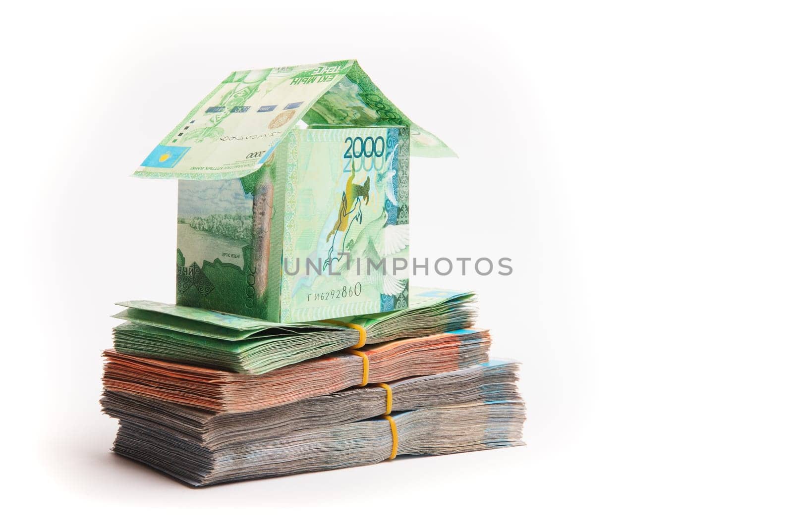 House made of banknotes of Kazakh money stands on packs of tenge. Mortgage concept, real estate appreciation, copy space.