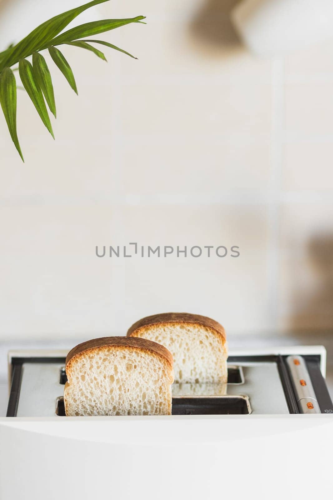 White toaster with white bread in a bright kitchen, high key, vertical copy space.