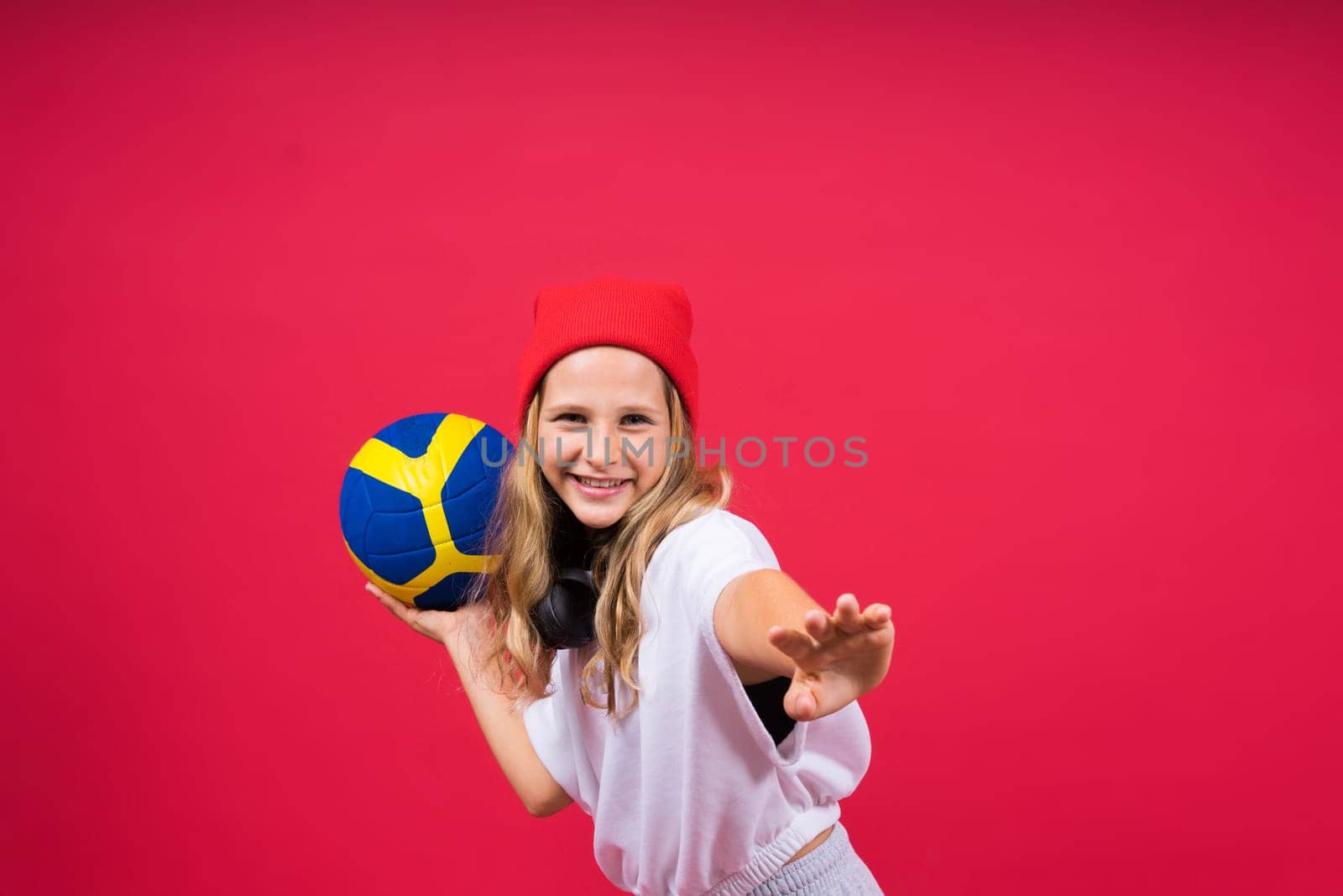 Portrait of cute eight year old girl in volleyball outfit isolated on a red yellow background