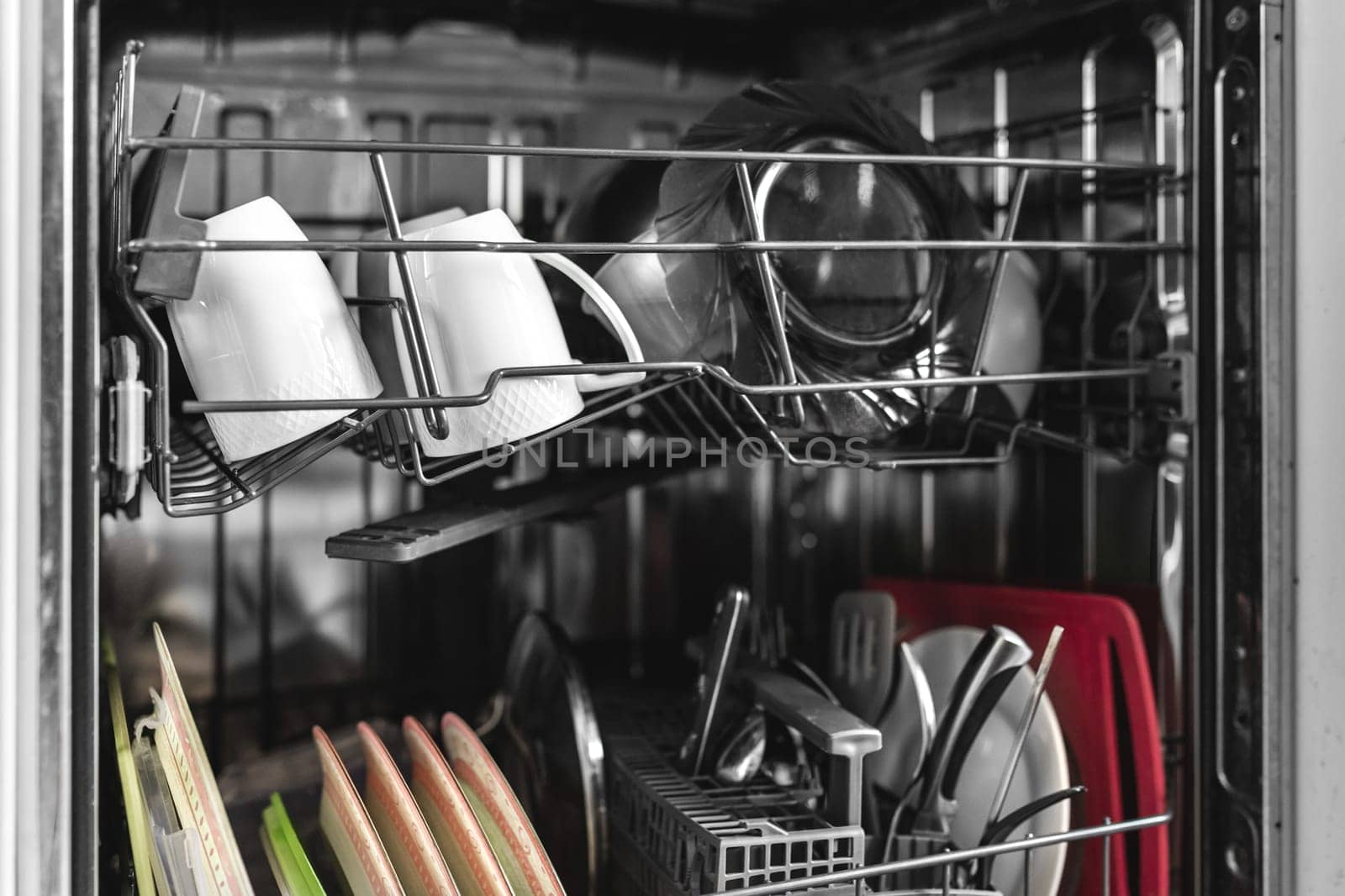 Close-up on open dishwasher machine with dishes built into the kitchen.