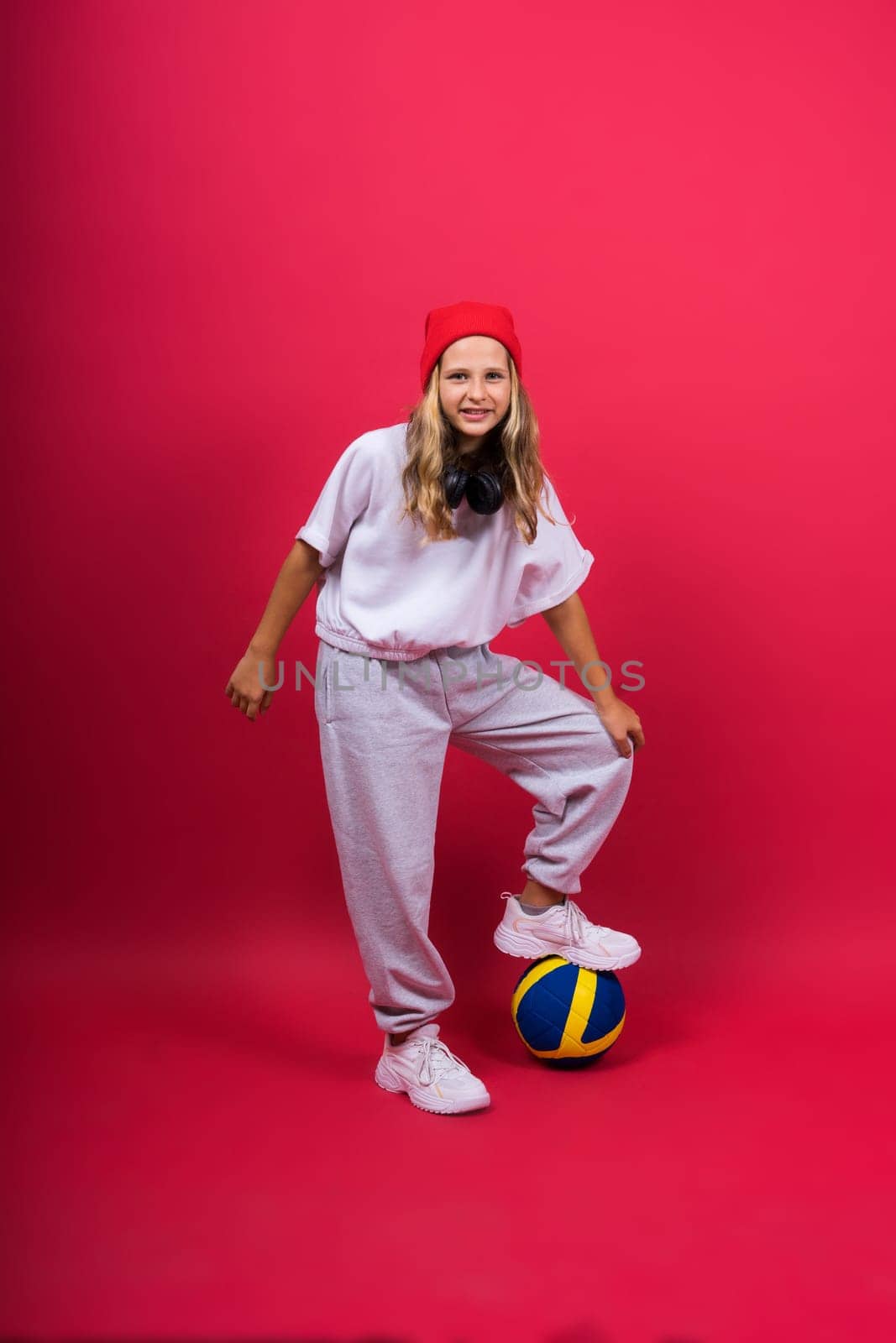 Portrait of cute eight year old girl in volleyball outfit isolated on a red yellow background