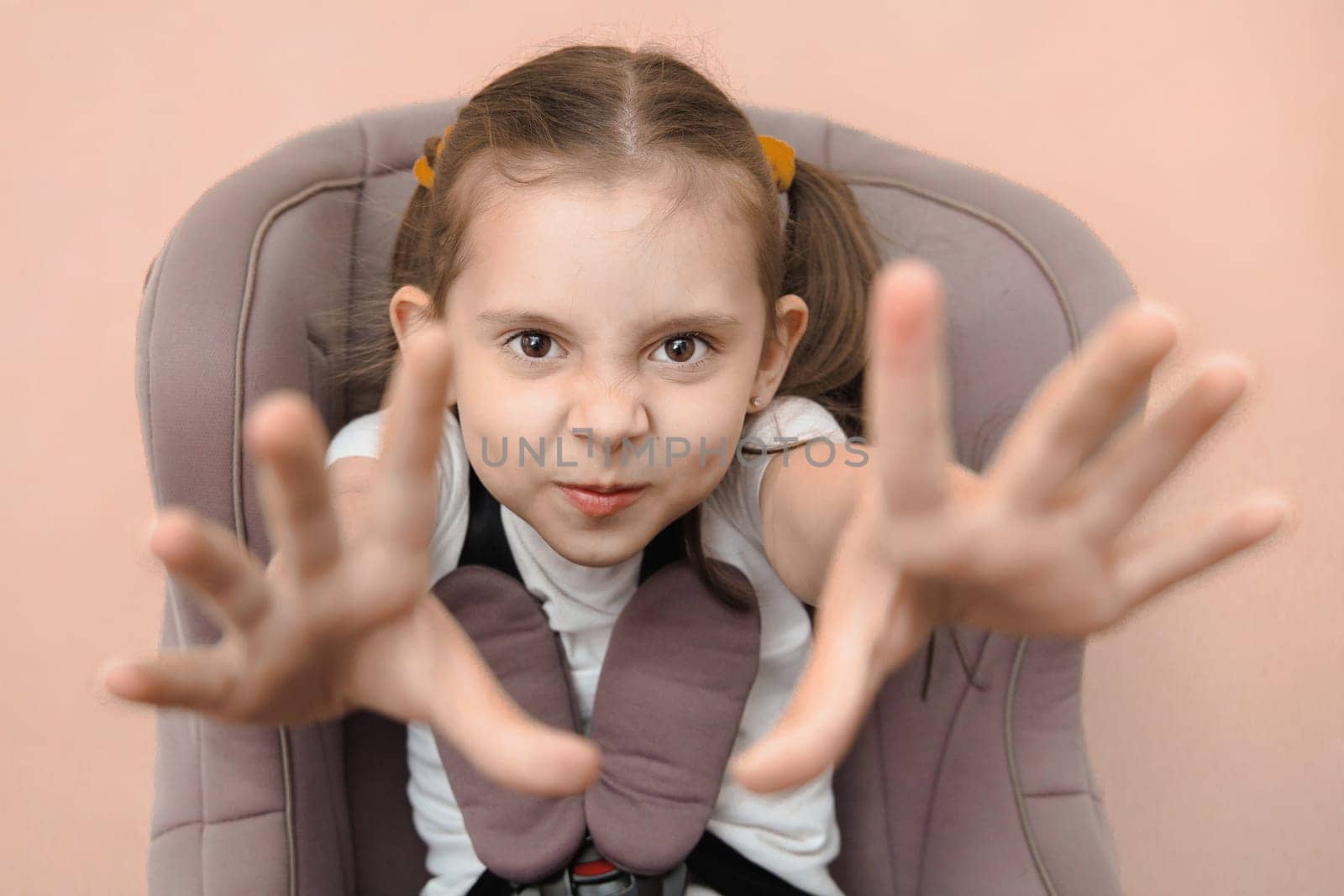 Funny studio portrait of a strapped child in a car seat.