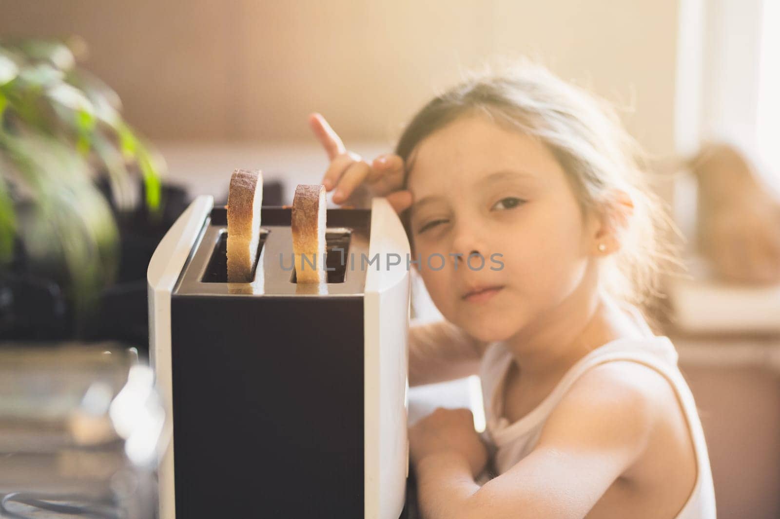 Childish lifestyle home portrait in kitchen with toaster. Selective soft focus.