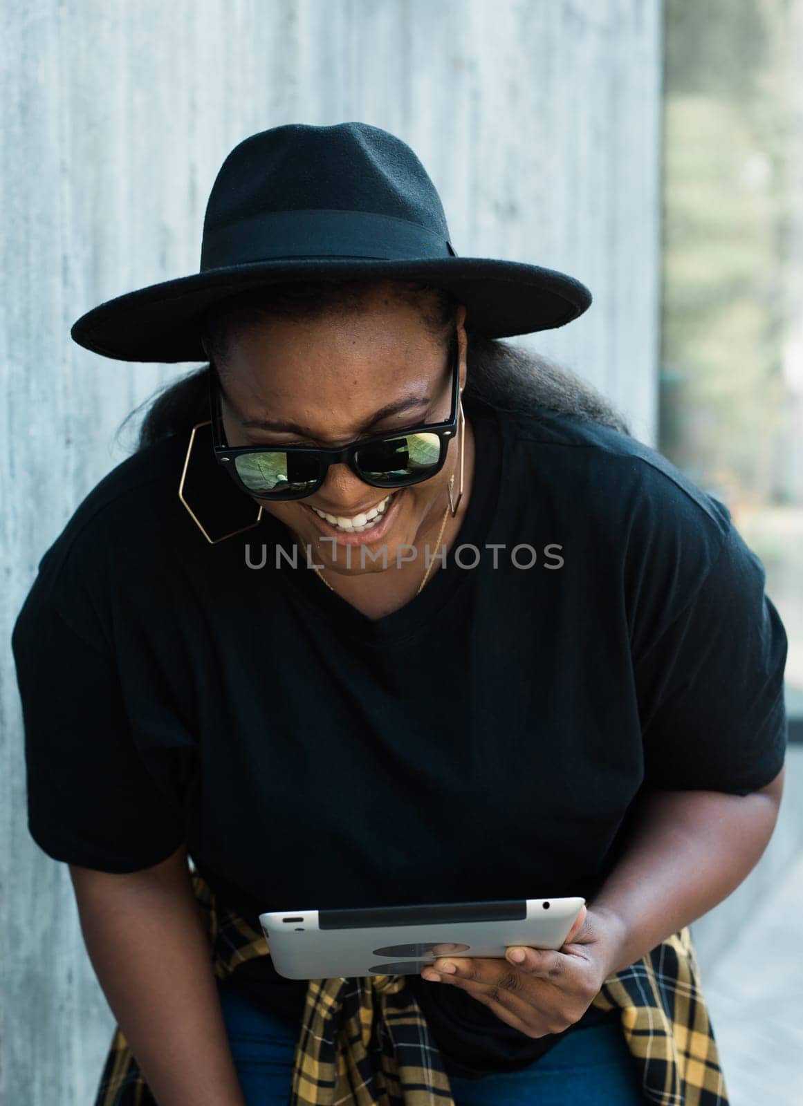 Beautiful African American woman using digital tablet, watching movie outdoors. Successful blogger influencer streaming video, communication online