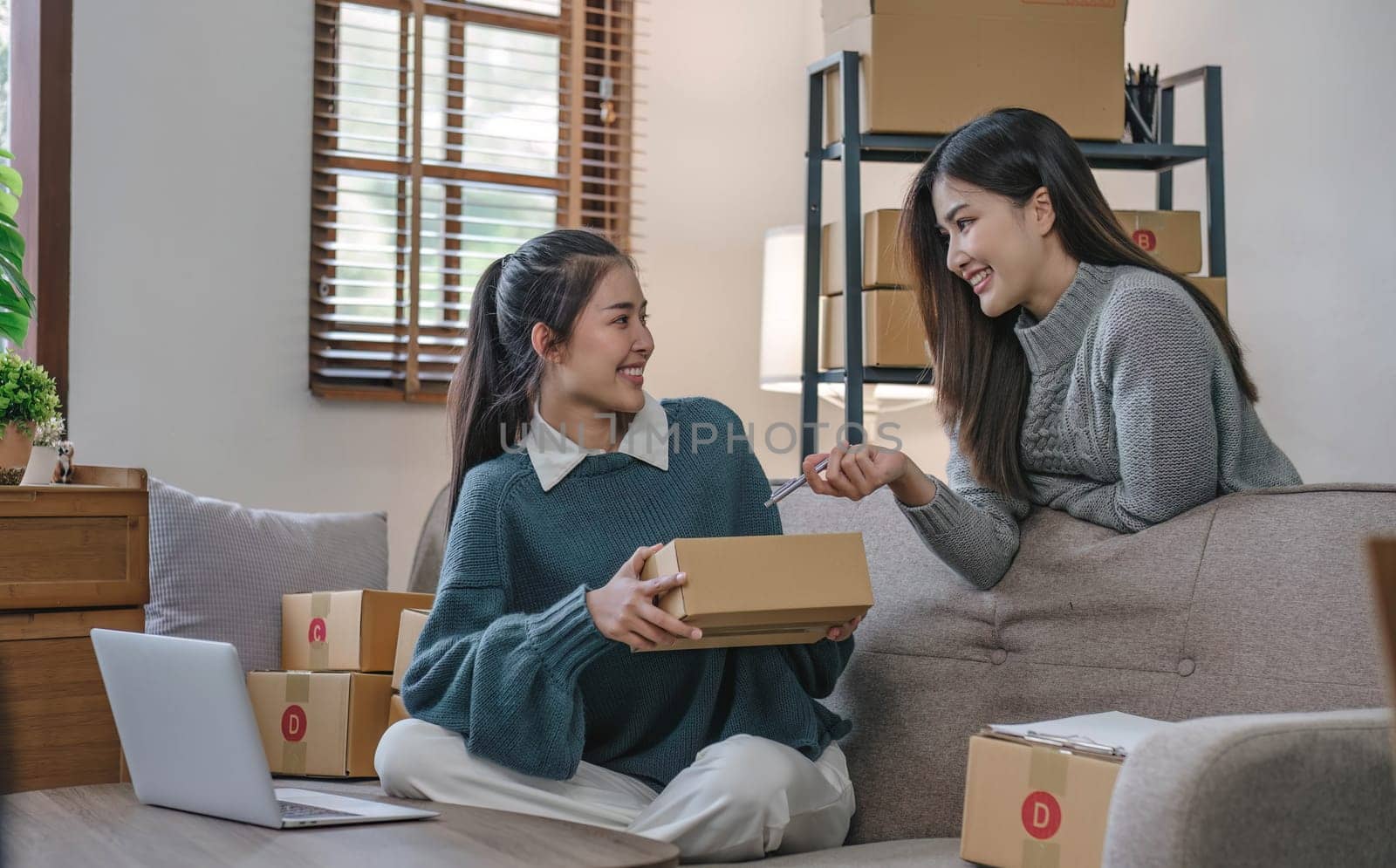 Two Asian Young business woman on sofa at home. startup sme small business entrepreneur SME distribution warehouse with parcel mail box. SME Online marketing and product packaging and delivery service..