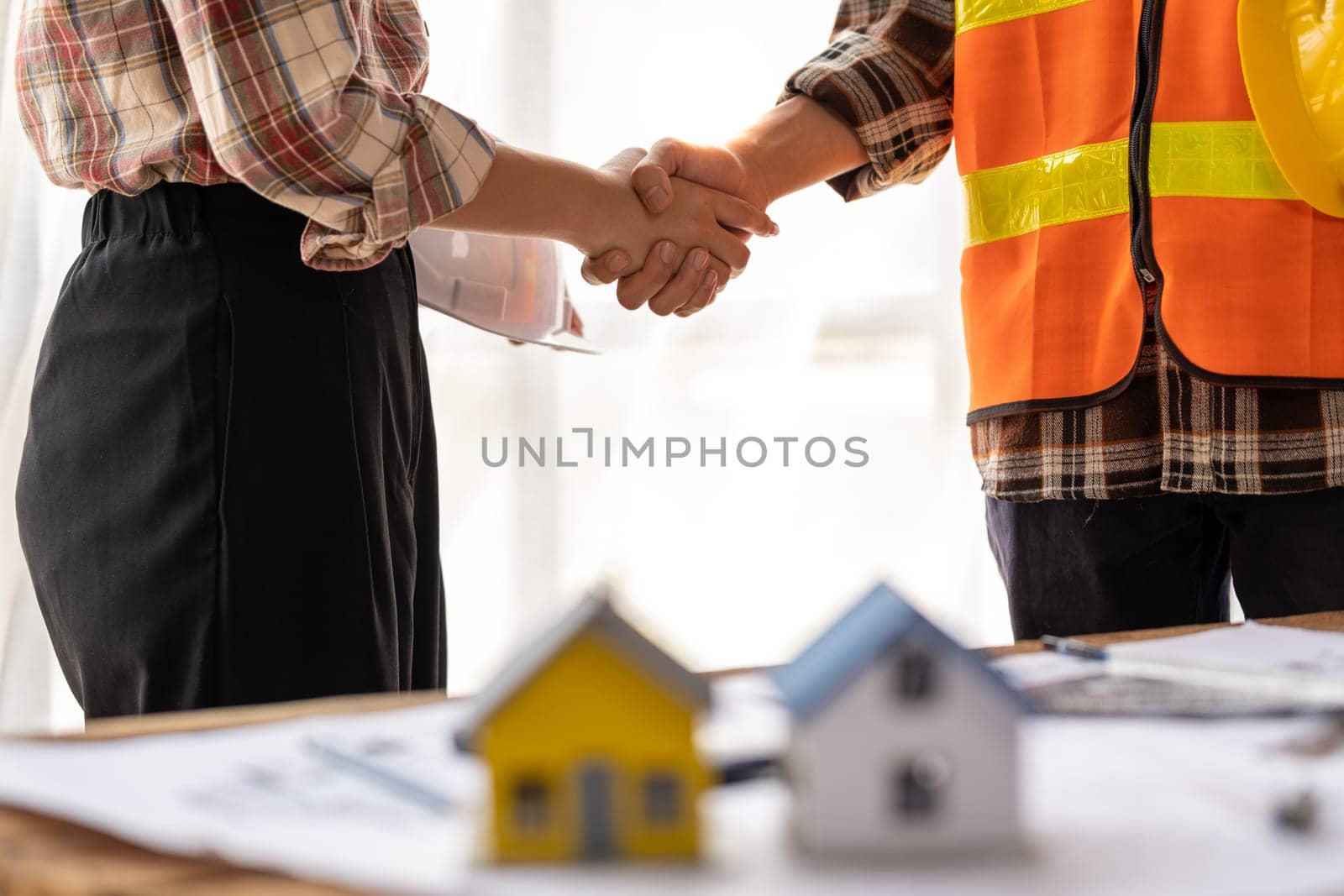 successful team engineers and business partner shaking hand, engineer and architecture shaking hand after finish an agreement, professional engineer plan to build a house. High quality photo