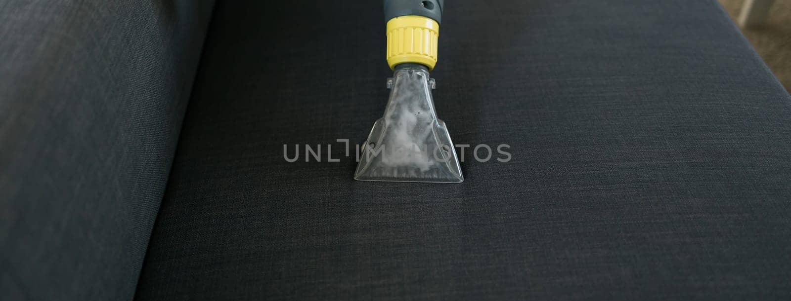 Banner Cleaning service company employee removing dirt from furniture in flat with professional equipment. Man arm cleaning sofa with washing vacuum cleaner close up copy space by Satura86