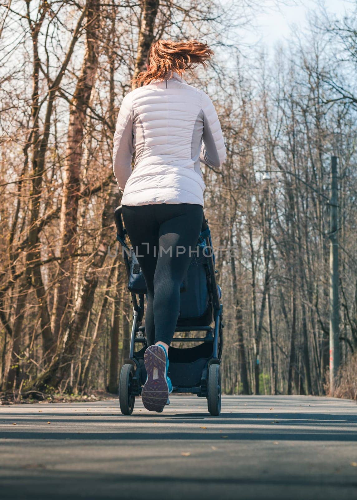 Lifestyle happy mother running with baby stroller in forest