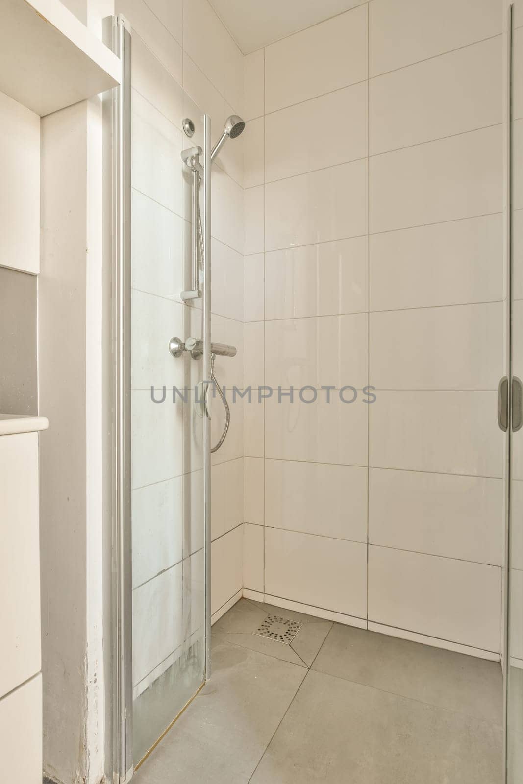 a bathroom with a shower stall in the corner and white tiles on the wall behind it, there is an open door
