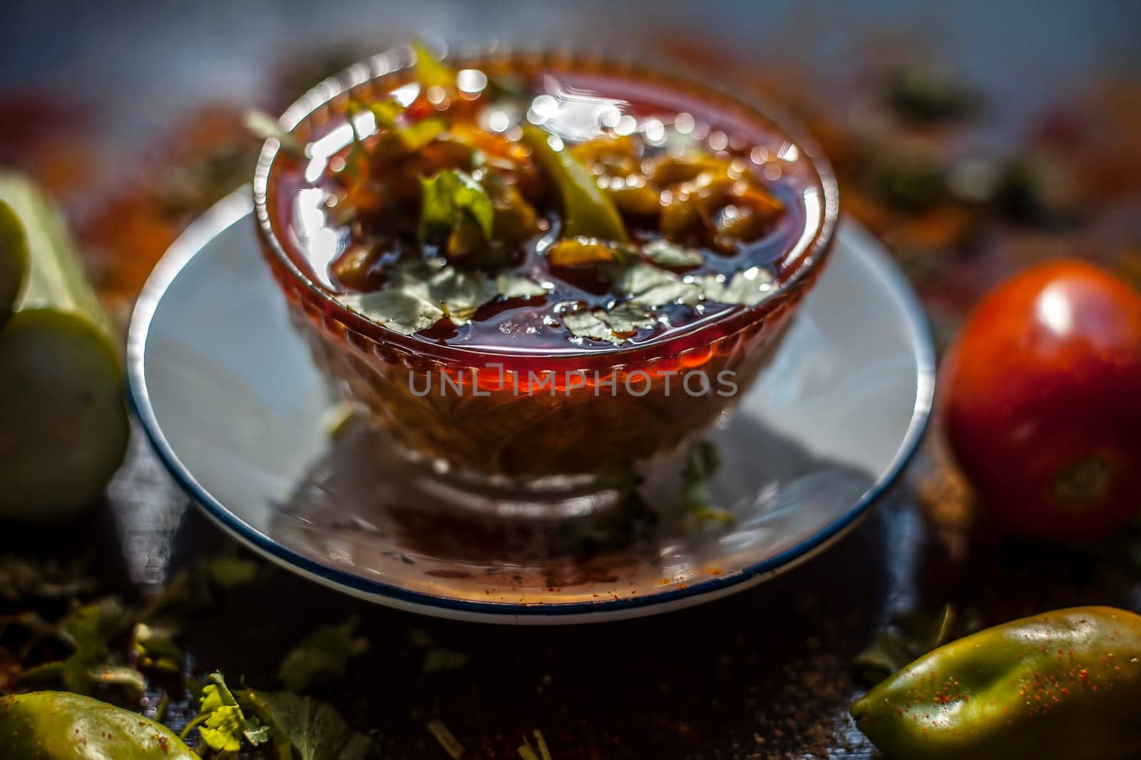 Close-up shot of fresh Indian Lunchtime dish luffa or Galka nu Shaak in a glass container along with all its ingredients on a rust-colored surface. by mirzamlk