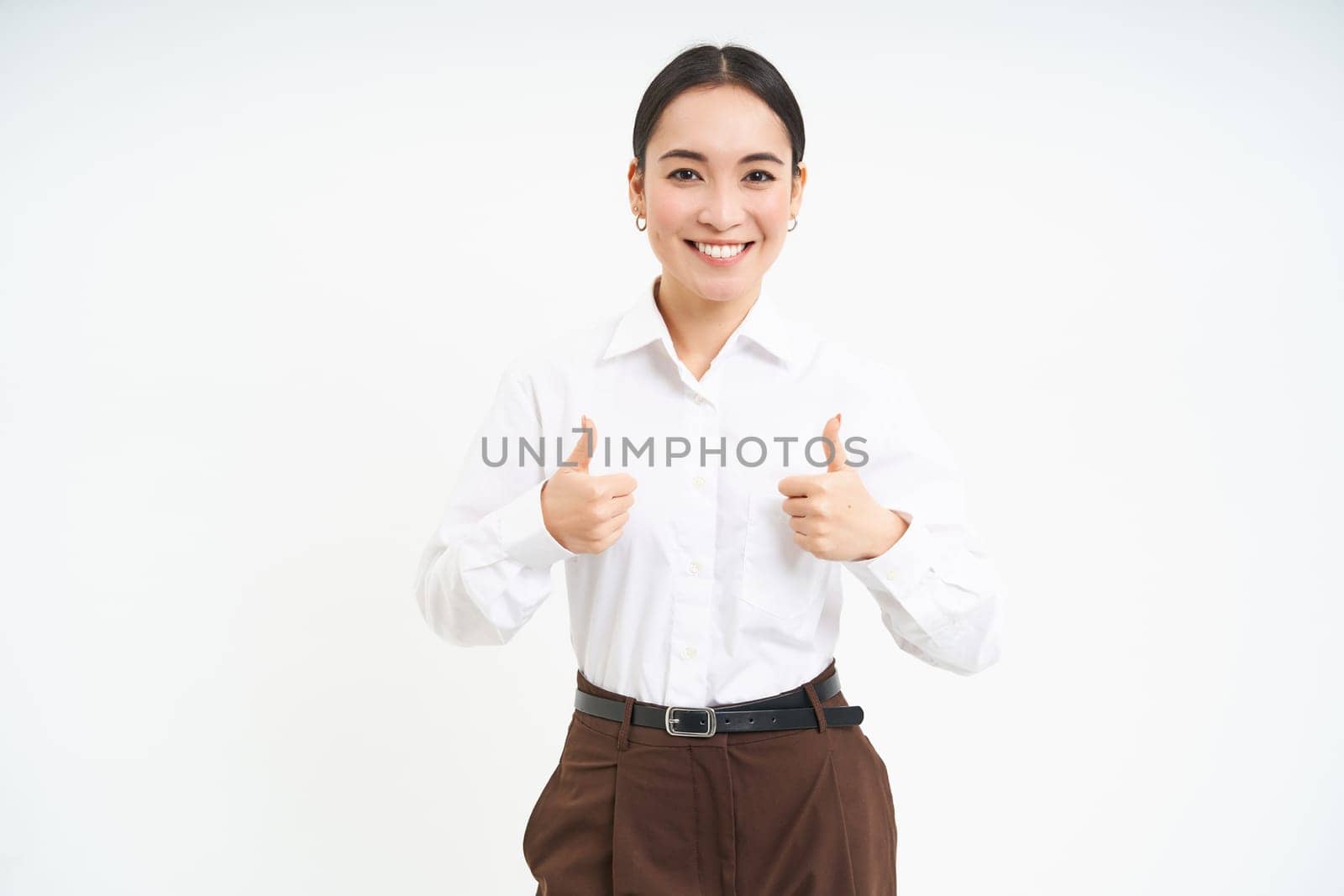 Smiling asian woman shows thumbs up, approves promo offer, recommends product, stands isolated over white background by Benzoix