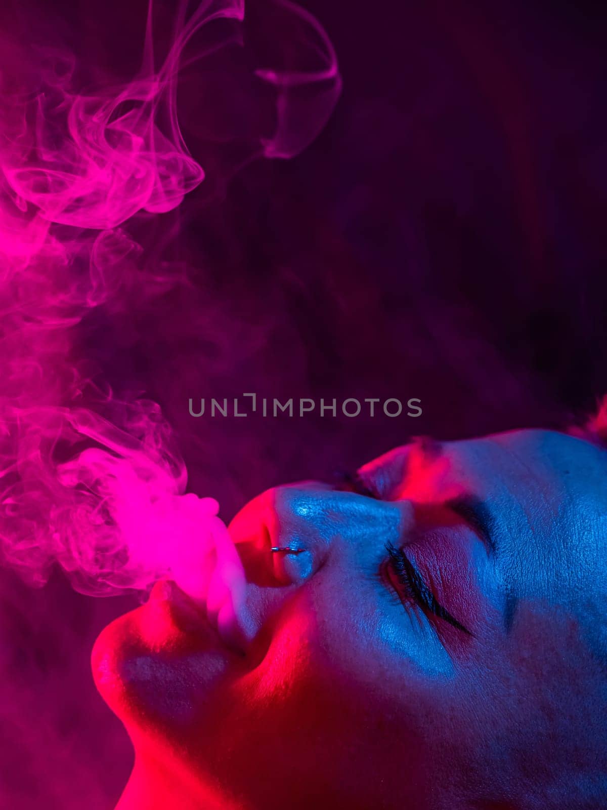 Asian woman with short haircut smoking in neon light. close-up portrait