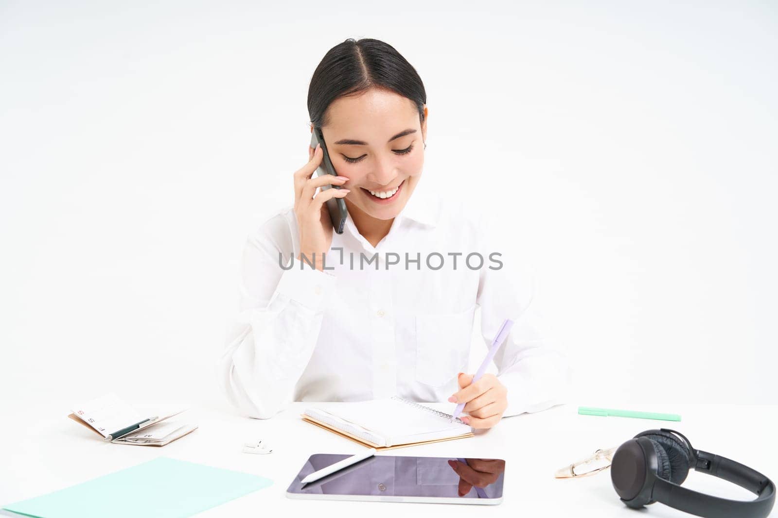 Portrait of smiling woman entrepreneur talking with her client on mobile phone, speaking with someone on cellphone, white background.