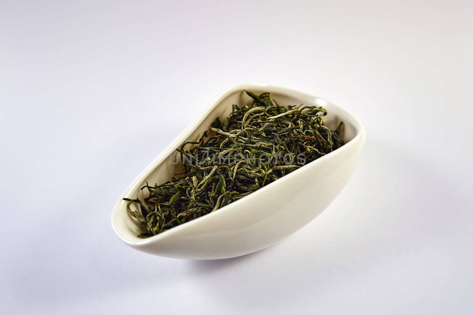 Dry green tea in a white porcelain bowl. Selective Focus