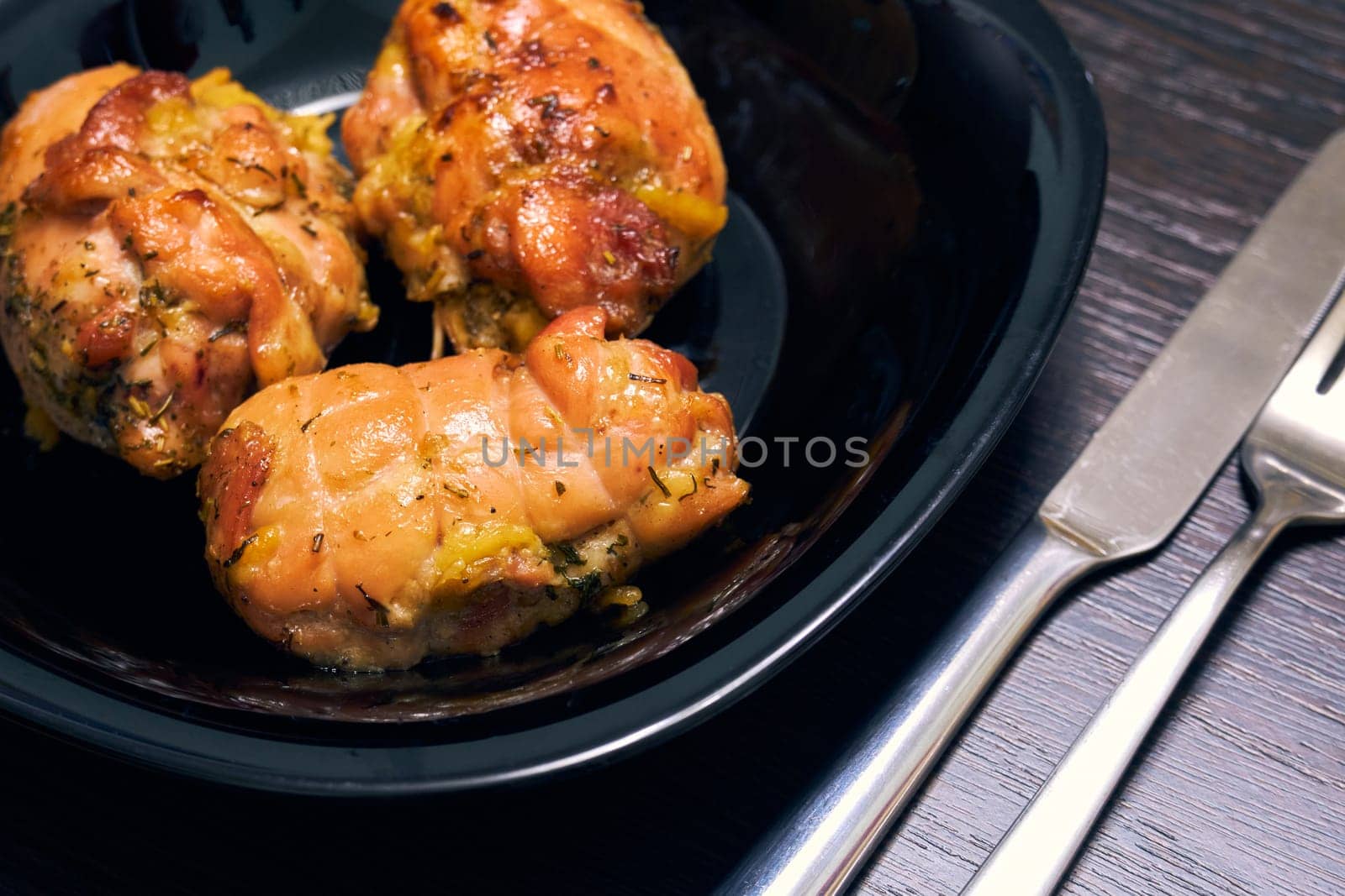 Homemade chicken roll on a black plate close-up