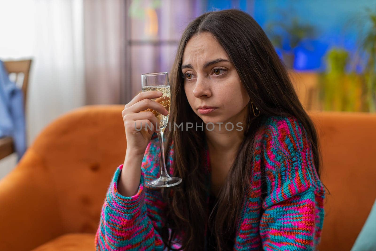 Sad young woman girl sitting at home looks pensive of unrequited love, suffers from unfair situation, drinking champagne, bad news. Problem break up, depressed feeling bad annoyed, burnout, bankruptcy