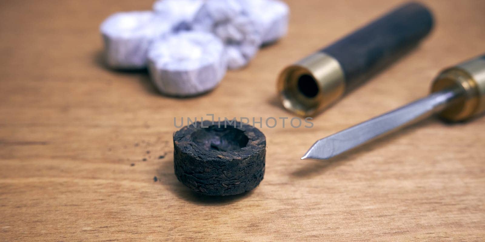 Pu-erh tea in the form of a round pressed briquette and a knife for grinding it on a wooden table