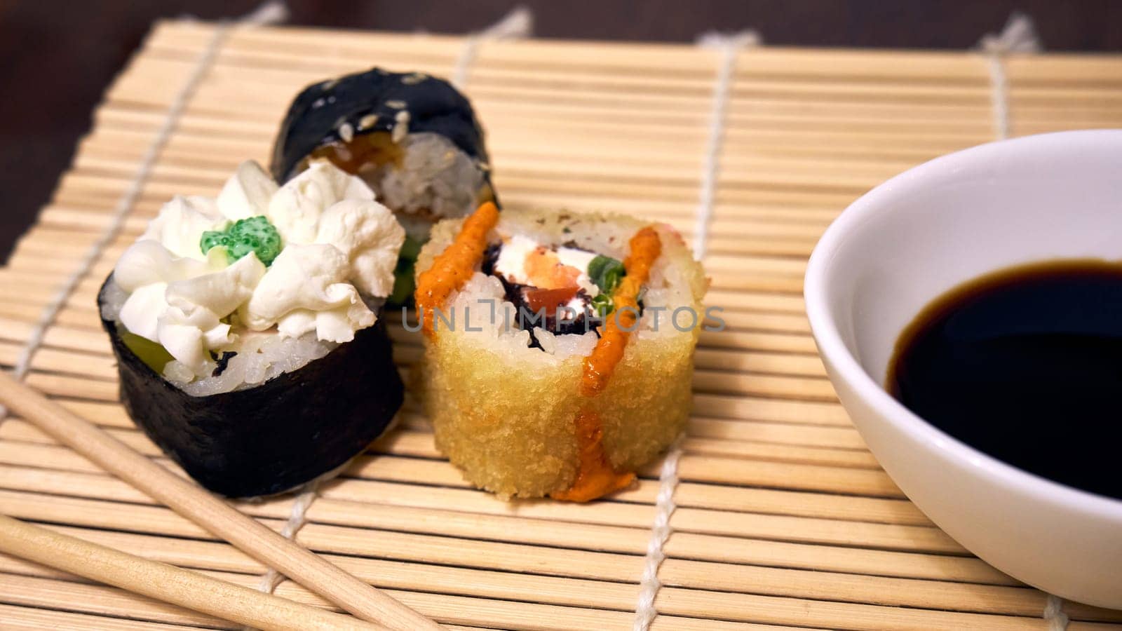 Sushi, chopsticks and soy sauce bowl on bamboo mat close-up